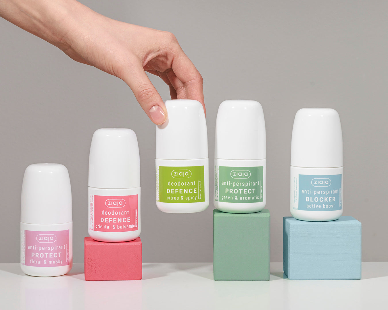 Roll-on deodorants with labels on colorful blocks against a gray background