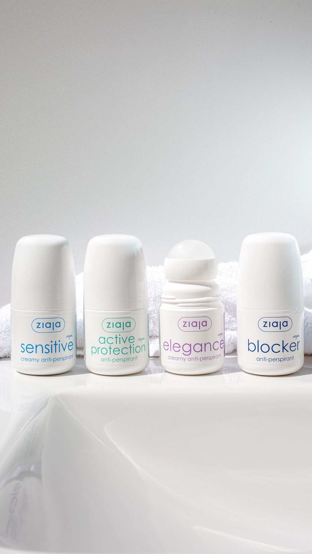 Four Ziaja anti-perspirants (Sensitive, Active Protection, Elegance, and Blocker) lined up on a bathroom surface with a white towel background.