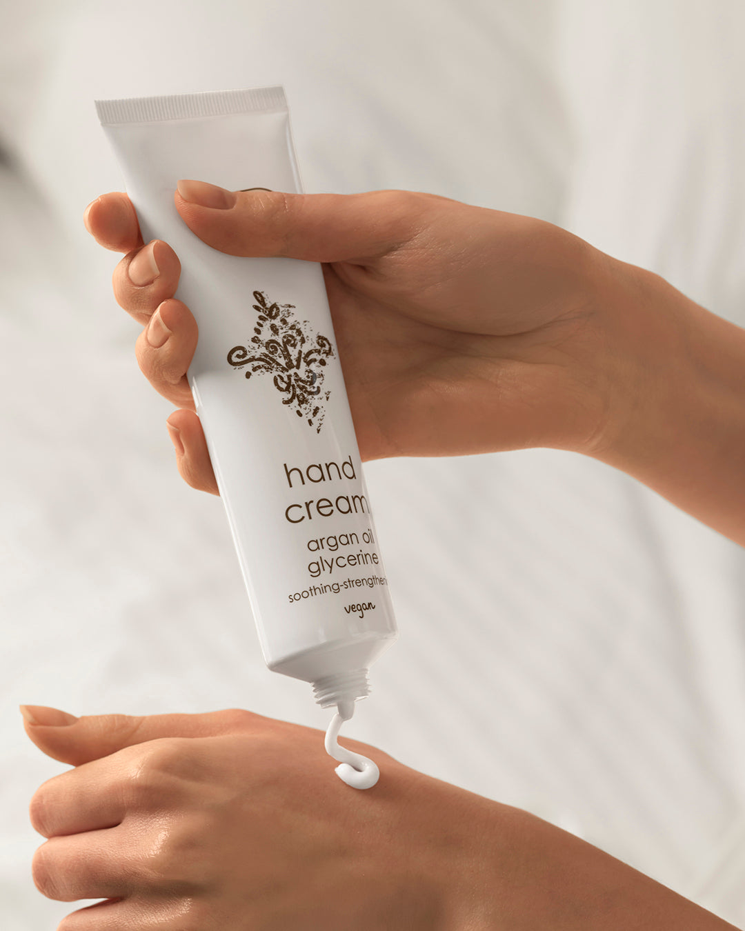 Hand holding a tube of hand cream against a white background