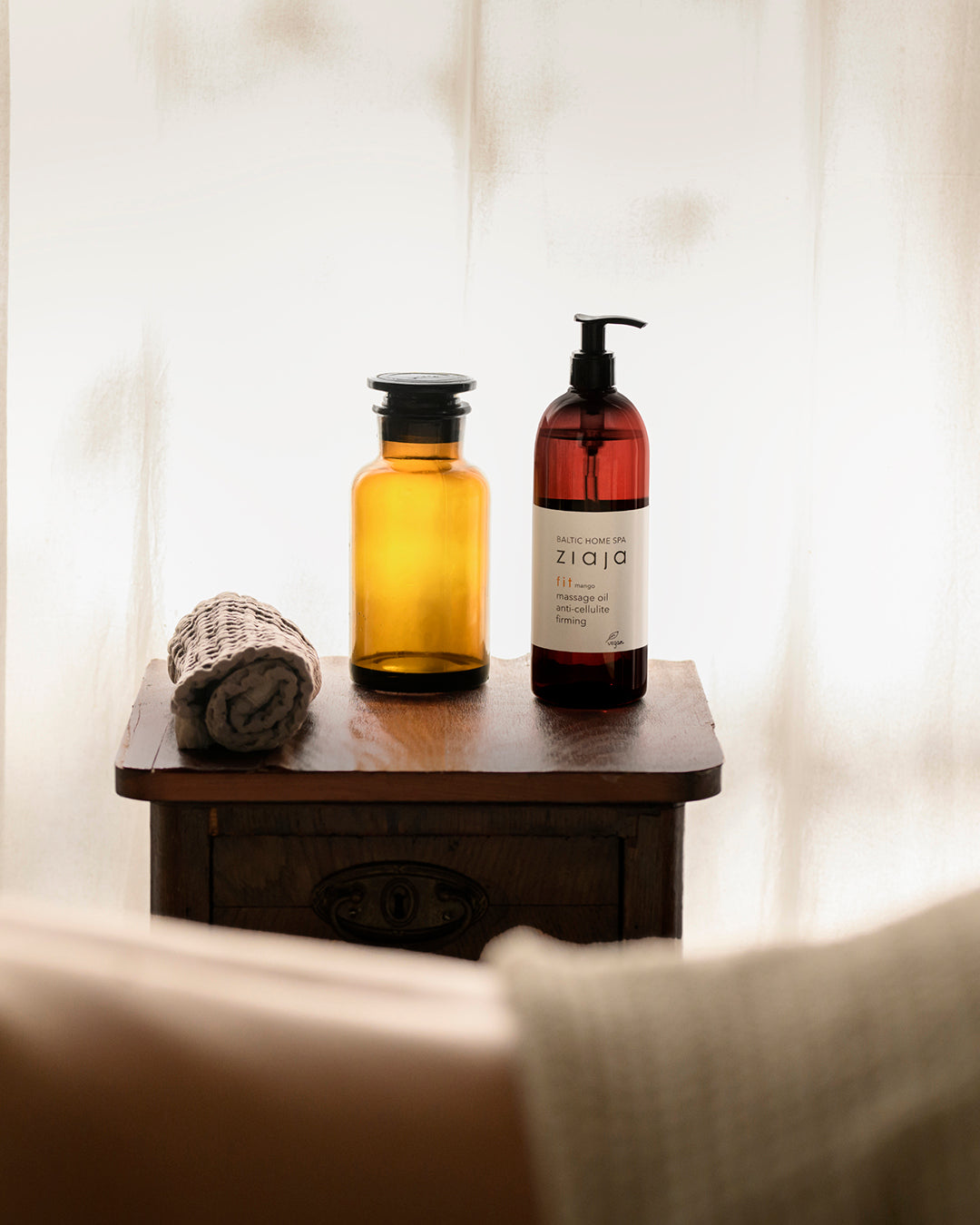 Two bottles and a towel on a wooden table with a blurred background.