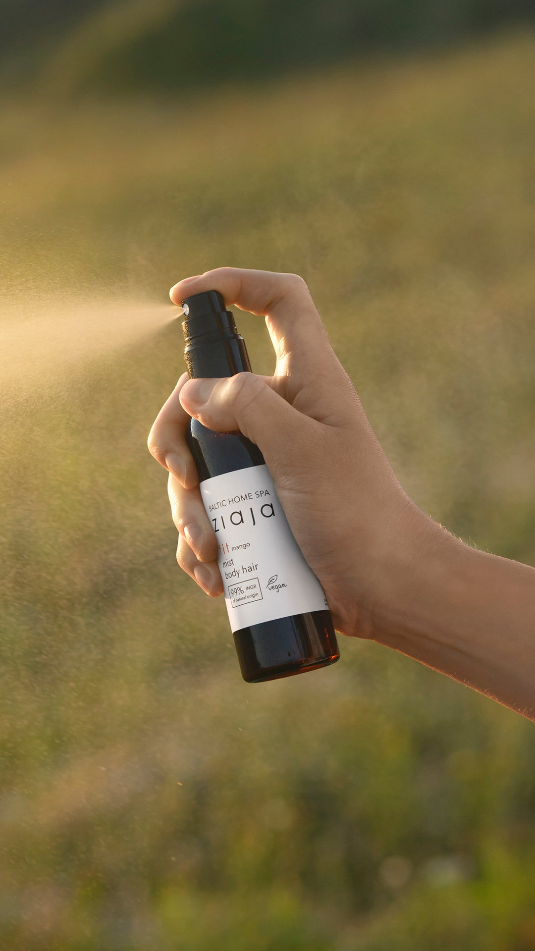 Hand holding a spray bottle in a field