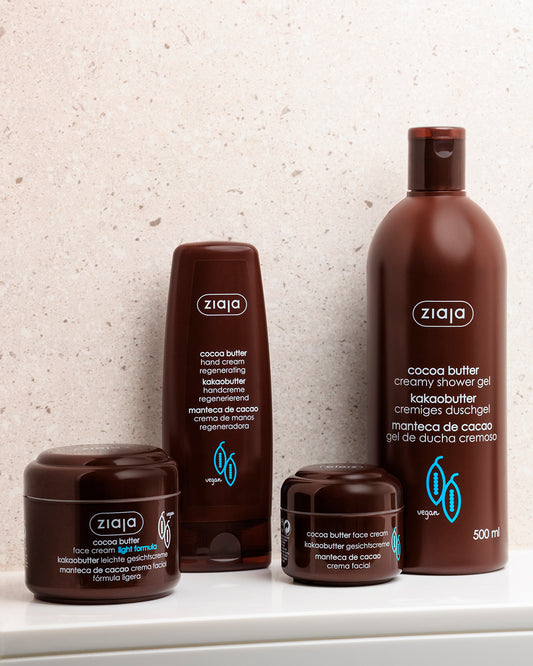 Ziaja cocoa butter skincare products on a white surface with a light gray textured wall background.