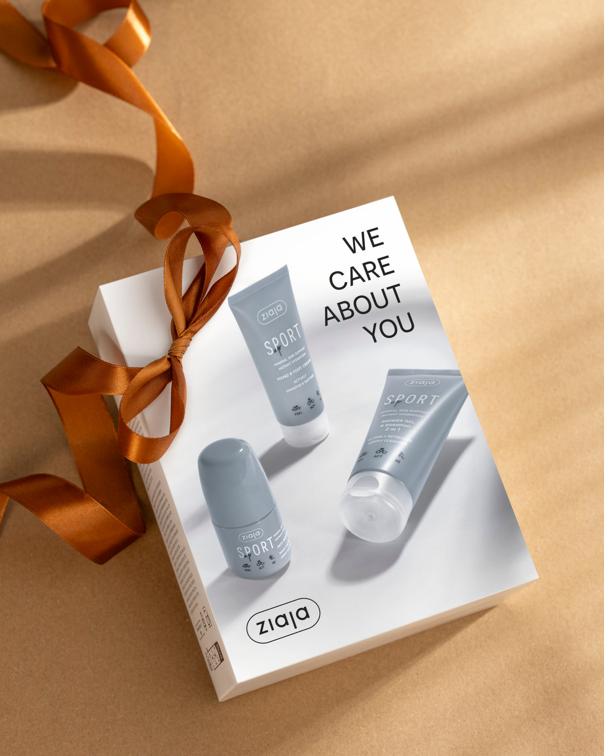 Ziaja Sport Up gift set with 2-in-1 shower gel and shampoo, hand and foot cream, and roll-on antiperspirant, presented in a white box with a copper satin ribbon.