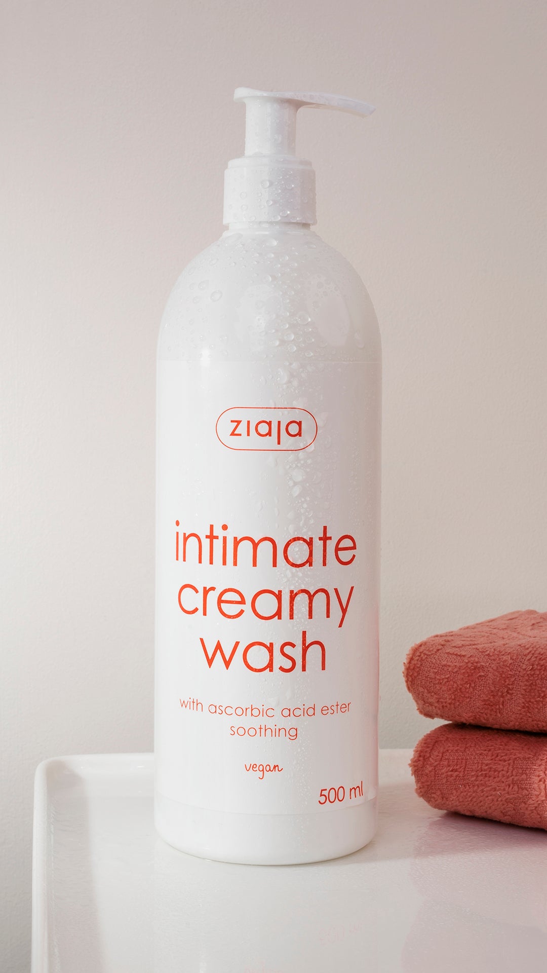 Bottle of Ziaja Intimate Creamy Wash on a white surface with towels in the background
