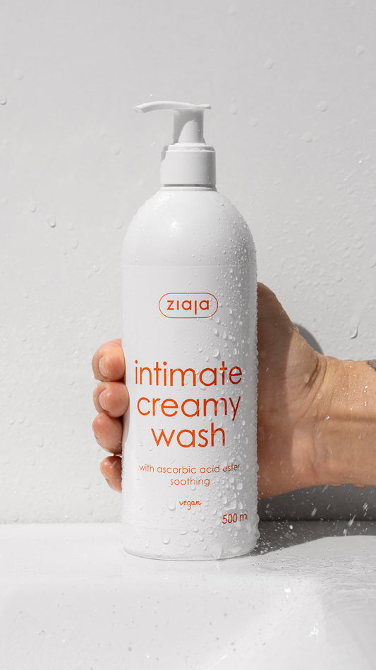 Hand holding a bottle of Ziaja intimate creamy wash against a light gray background