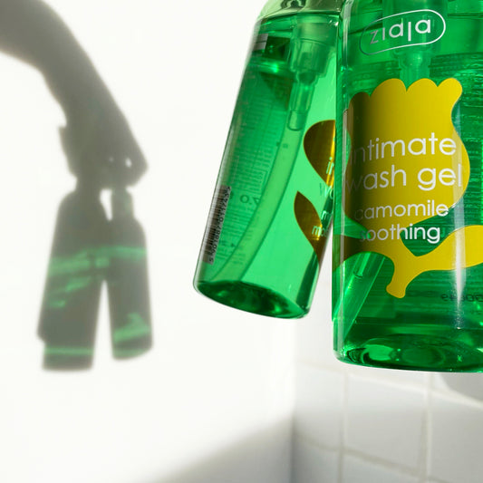 two clear bottles of Ziaja Intimate Wash with camomile with transparent green liquid against white background.