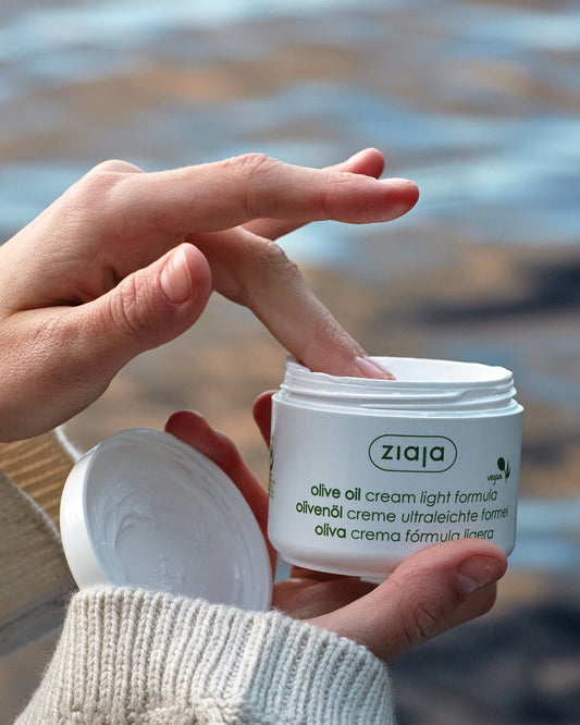 Person applying Ziaja olive oil cream to their hand with a blurred background