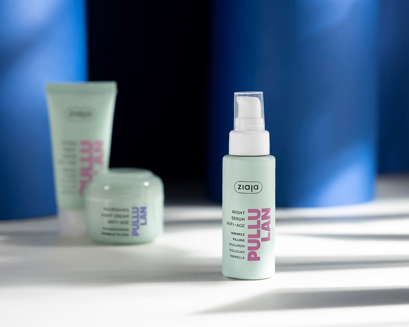 Ziaja skincare products on a reflective surface with a blue gradient background
