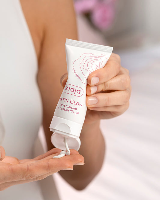 Person applying Ziaja Satin Glow cream to their hand against a neutral background