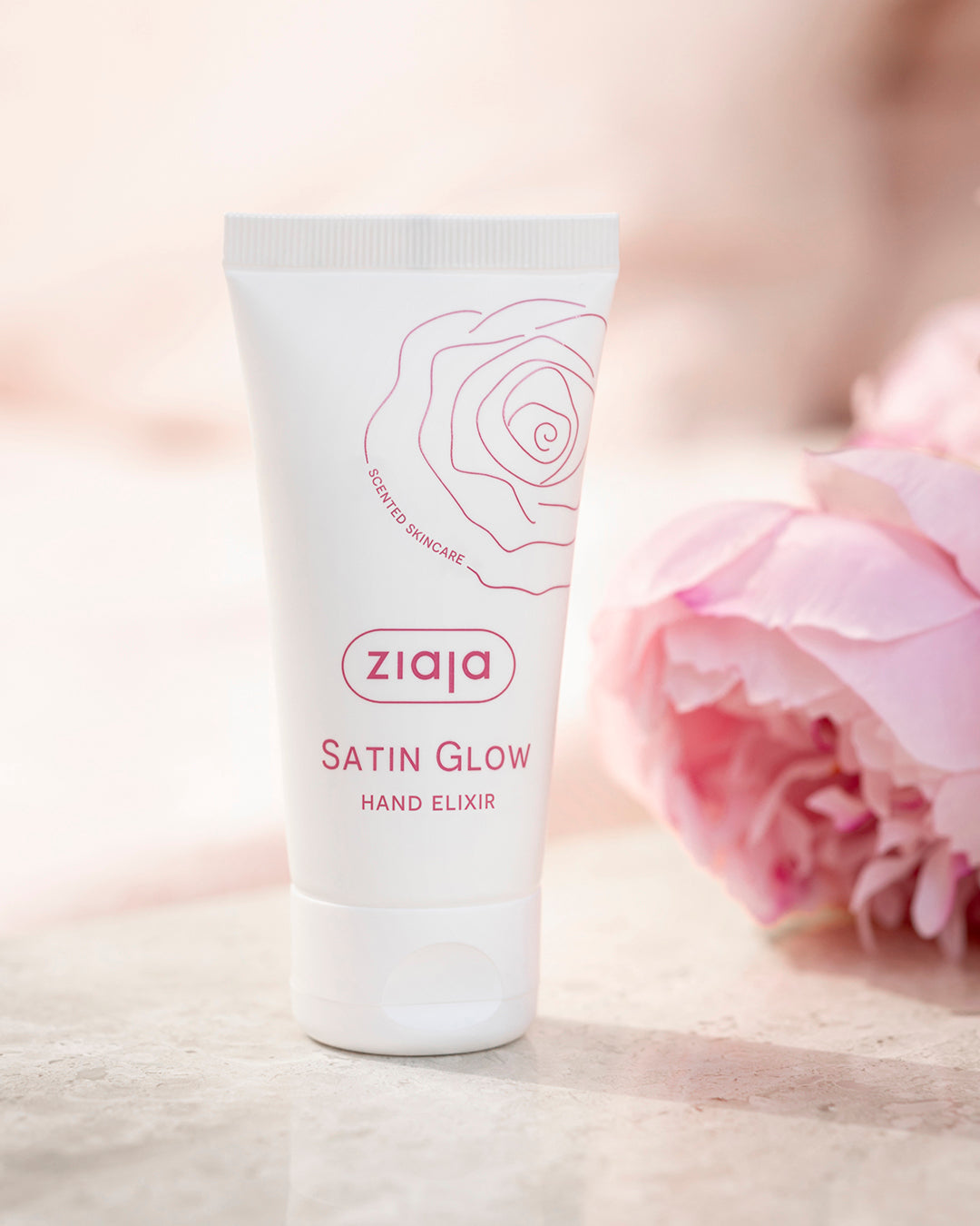Ziaja Satin Glow Hand Elixir tube with a pink flower on a light background