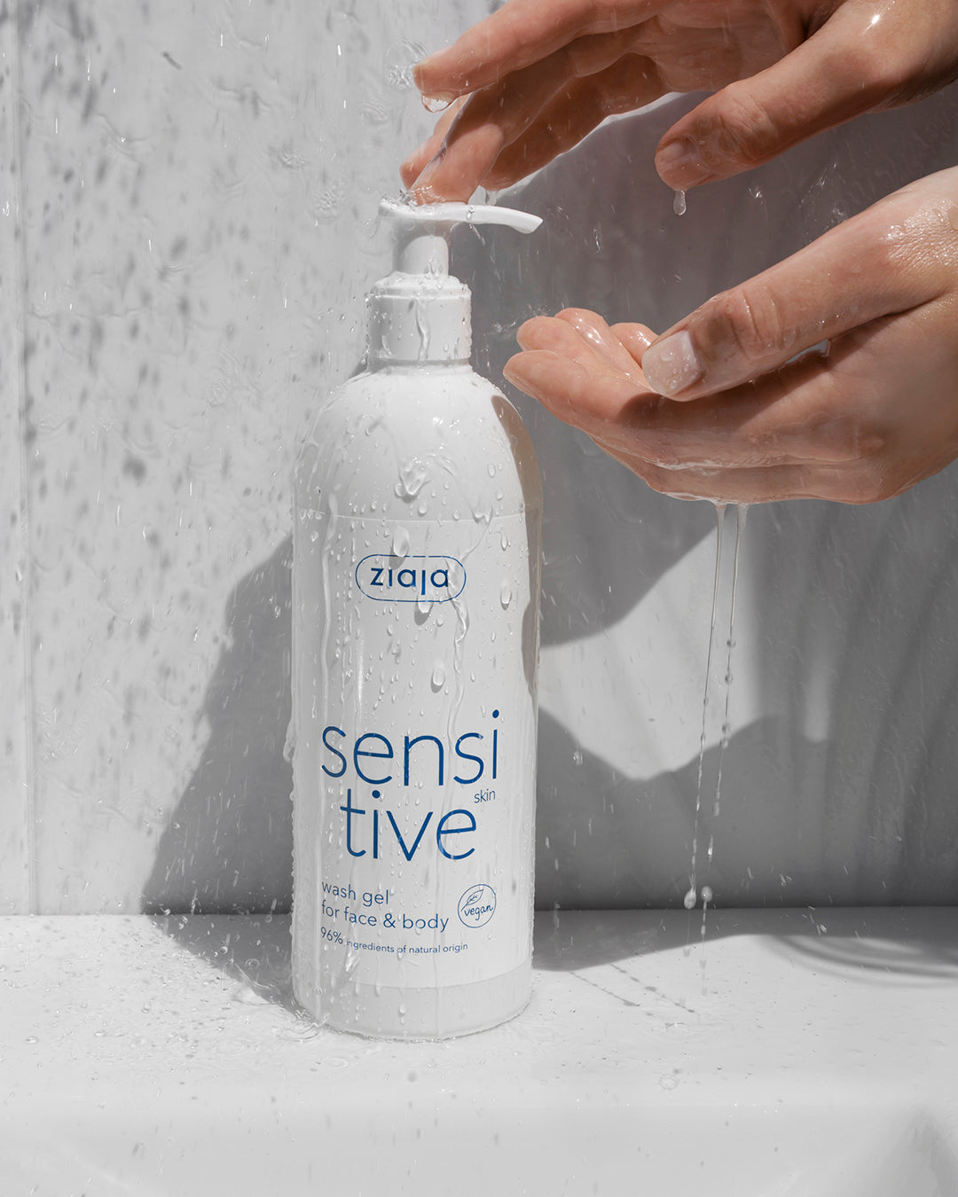 Ziaja Sensitive Creamy Wash Gel For Face And Body 400Ml bottle with hands under running water in the background