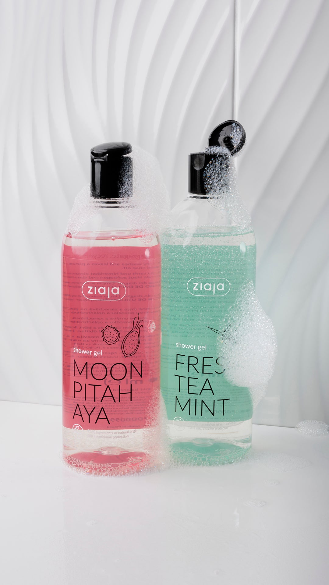 Two bottles of Ziaja shower gel, one pink and one green, on a white background.