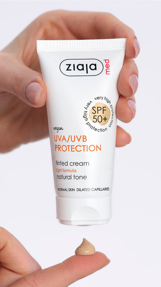 Hand holding a tube of Ziaja Med sunscreen with a small amount on the tip of the finger.