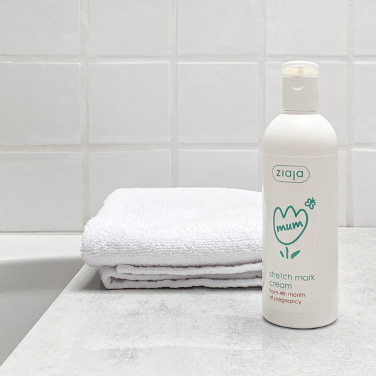 Ziaja Mum stretch mark cream bottle on a bathroom counter with a towel in the background.