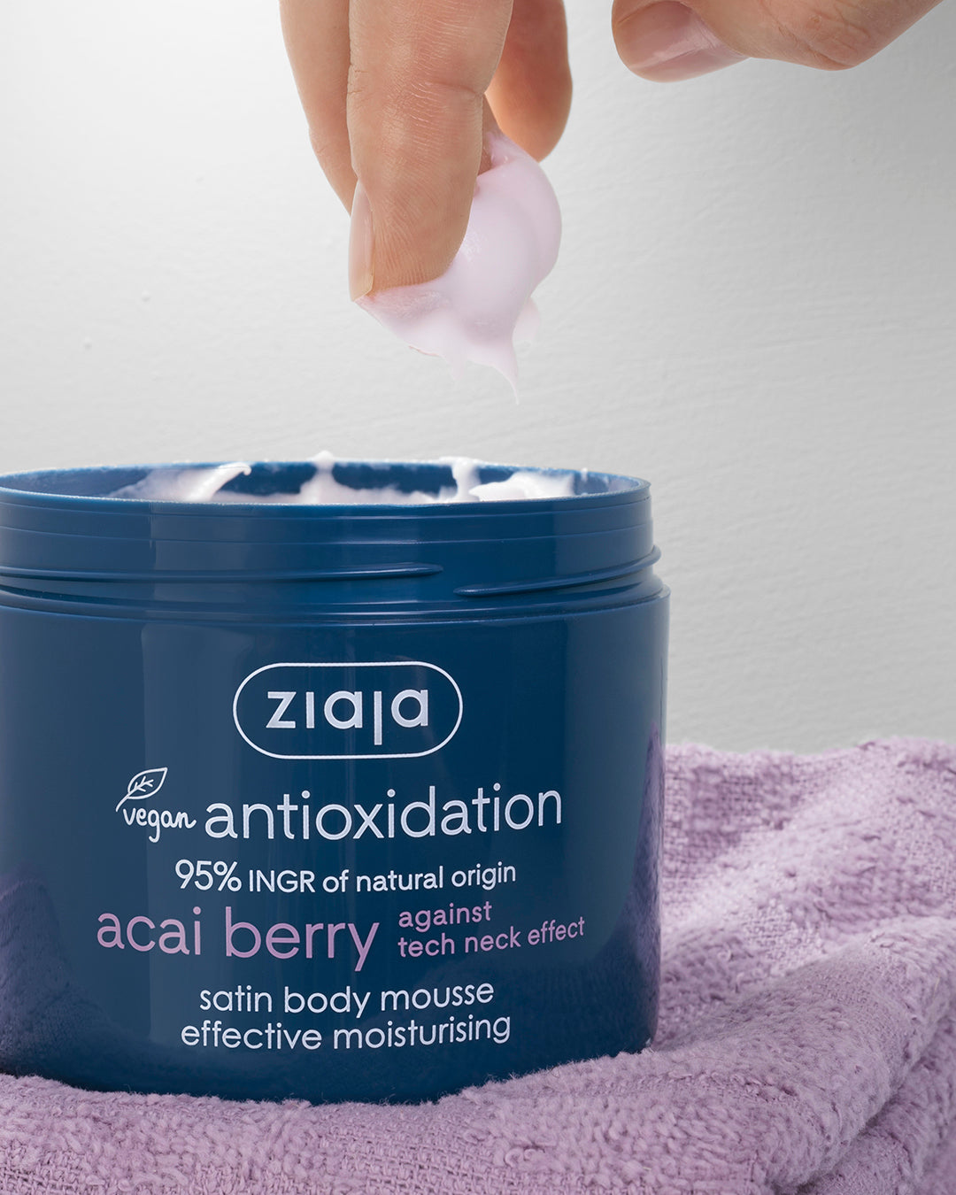 Ziaja antioxidant acai berry body mousse being applied with a hand against a light background