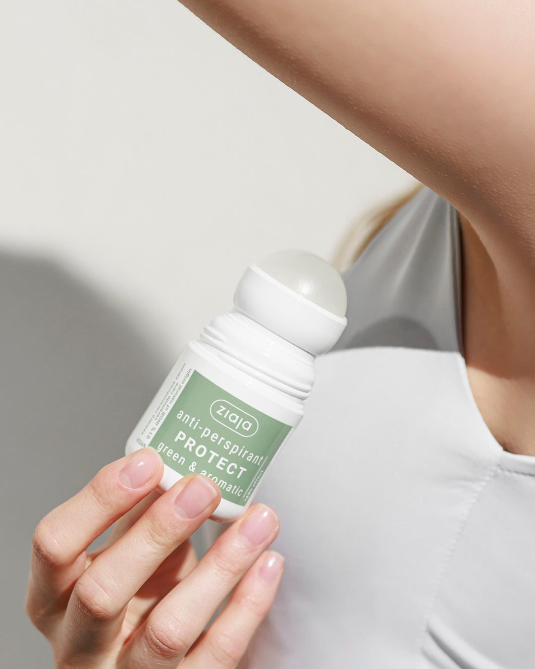 Person holding a Ziaja anti-perspirant bottle against a neutral background