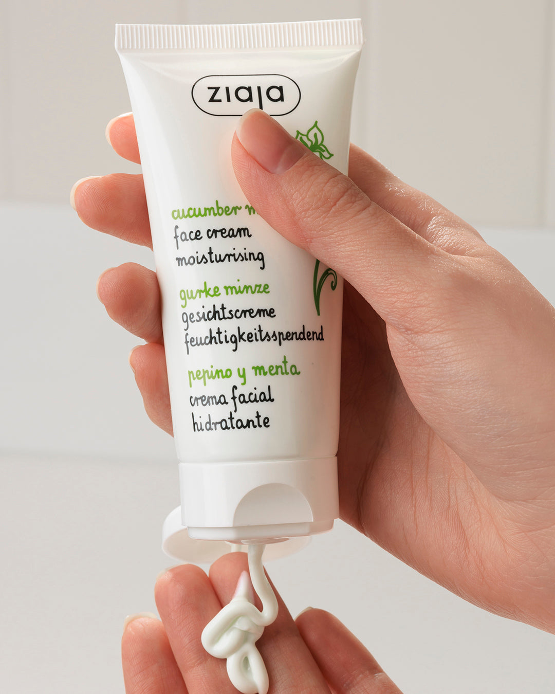 Hand holding a Ziaja cucumber mint face cream tube against a white background