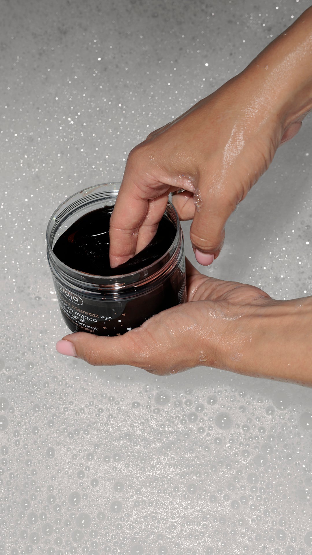 Ziaja Chocolate Fusion Bath Jelly Soap – hands holding an open jar of dark bath jelly over bubbly bath water.