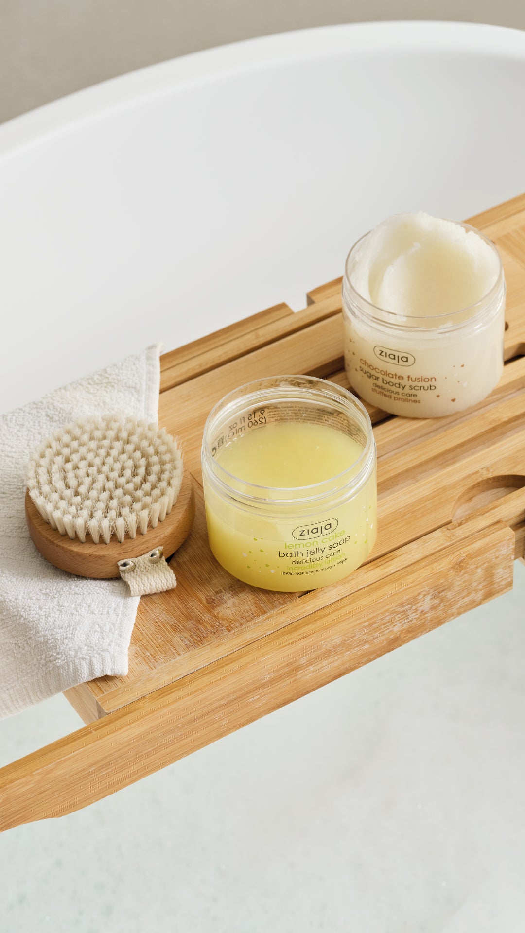 Two jars of body butter and a brush on a wooden tray with a neutral background