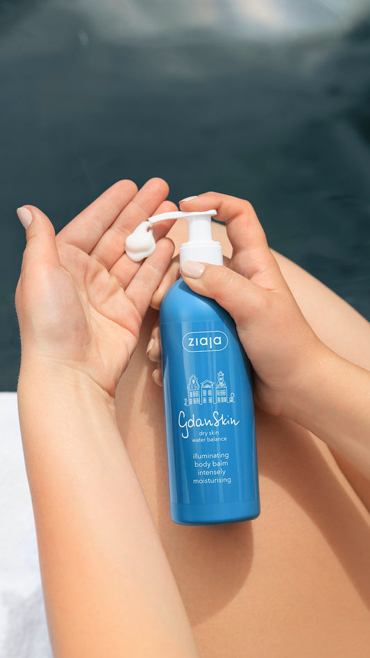 Person holding a blue bottle labeled 'ziaja' with a white pump against a blurred background