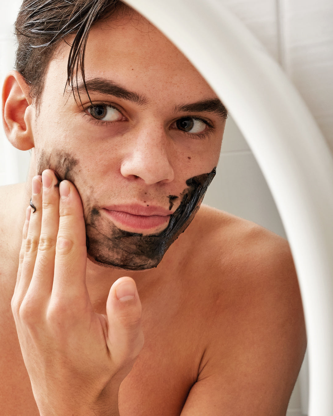 Man applying Ziaja Jeju cleansing and smoothing face mask with binchotan charcoal to his cheeks and chin