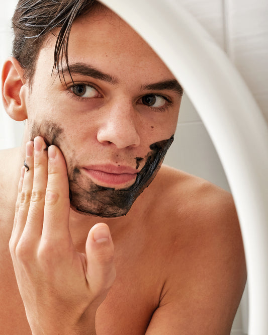 Man applying Ziaja Jeju cleansing and smoothing face mask with binchotan charcoal to his cheeks and chin