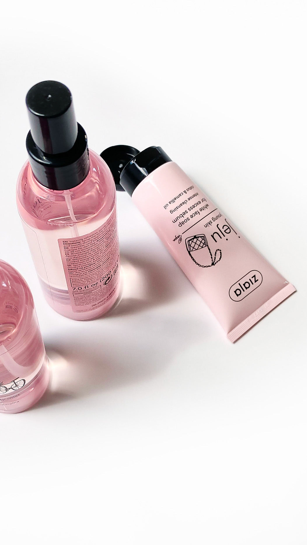 Three skincare products including a bottle and two tubes on a white background