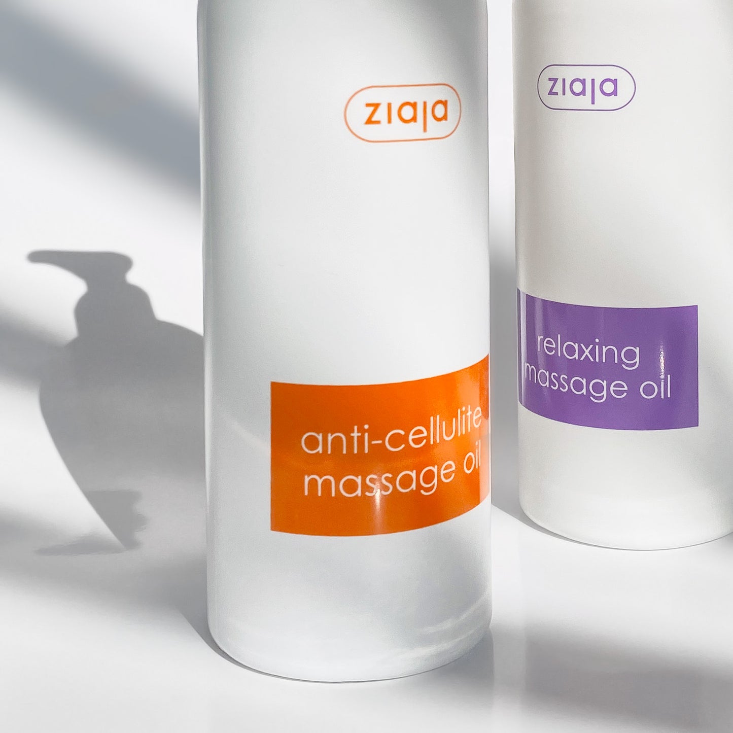 Two bottles of Ziaja massage oil on a white background