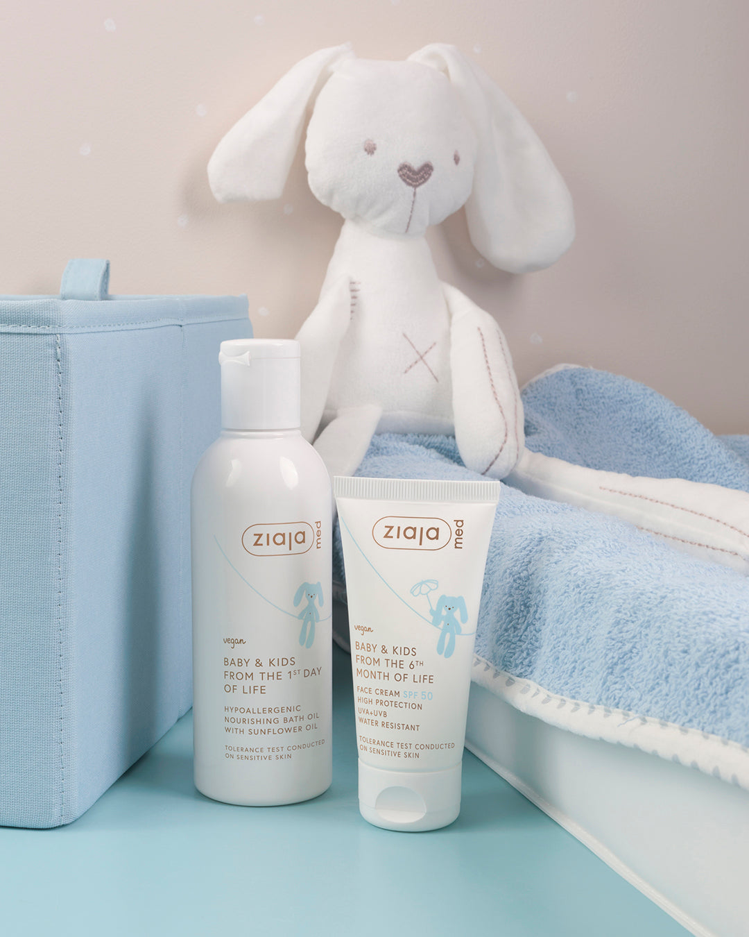 Ziaja Med Baby & Kids Face Cream SPF 50 (50 ml) tube next to Ziaja Med Baby & Kids Nourishing Bath Oil, with a soft toy and blanket in the background.