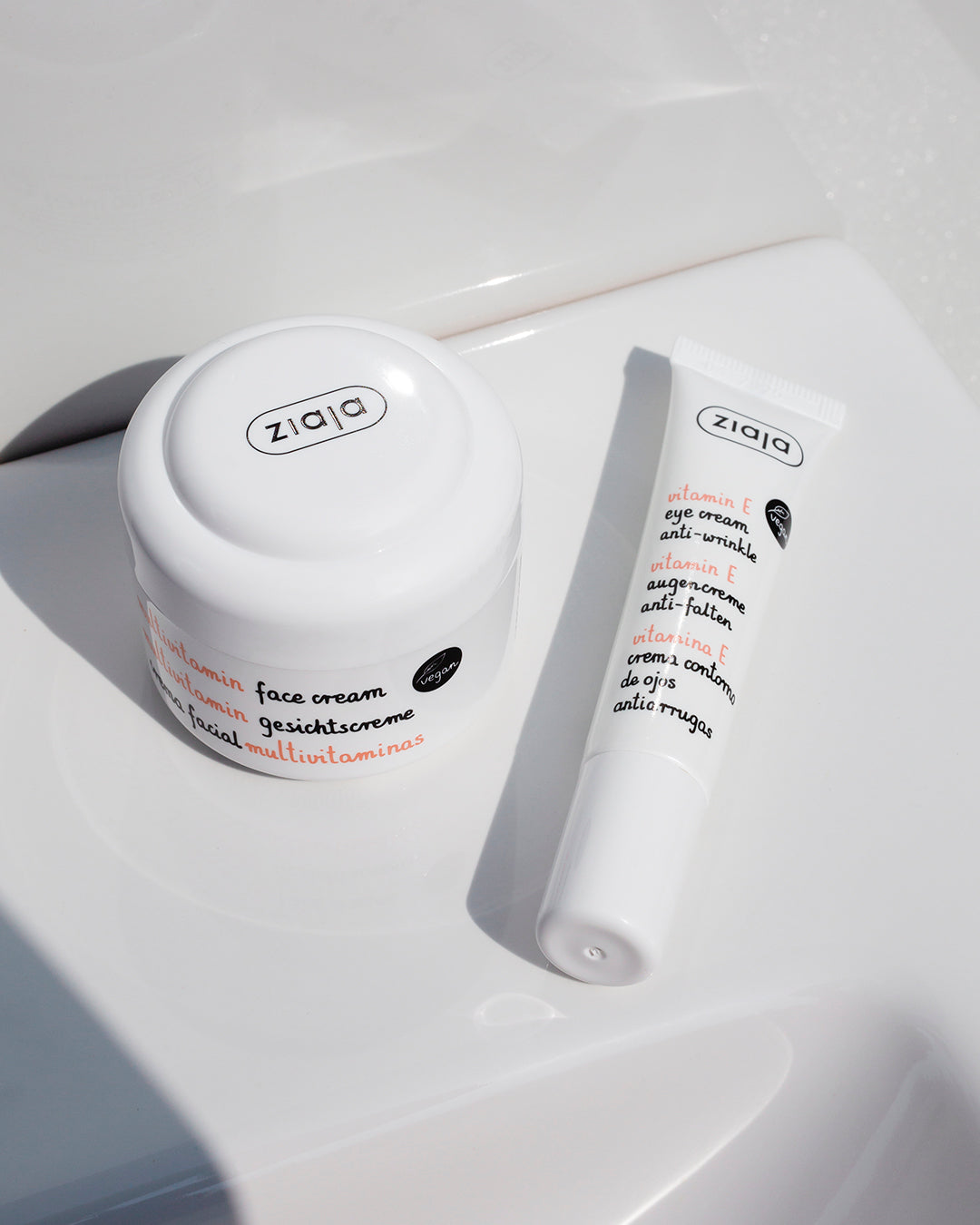 Ziaja Multivitamin Moisturizing Face Cream 50Ml jar and tube of Ziaja Vitamin E Eye Cream 15Ml on a white surface