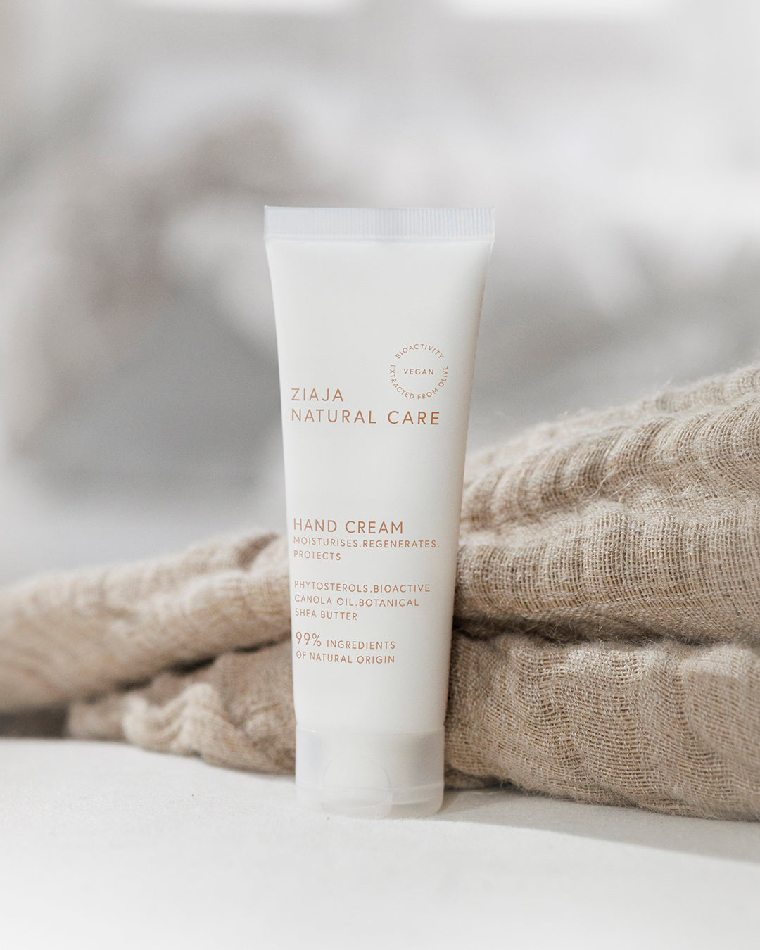 Ziaja Natural Care hand cream tube on a textured fabric background