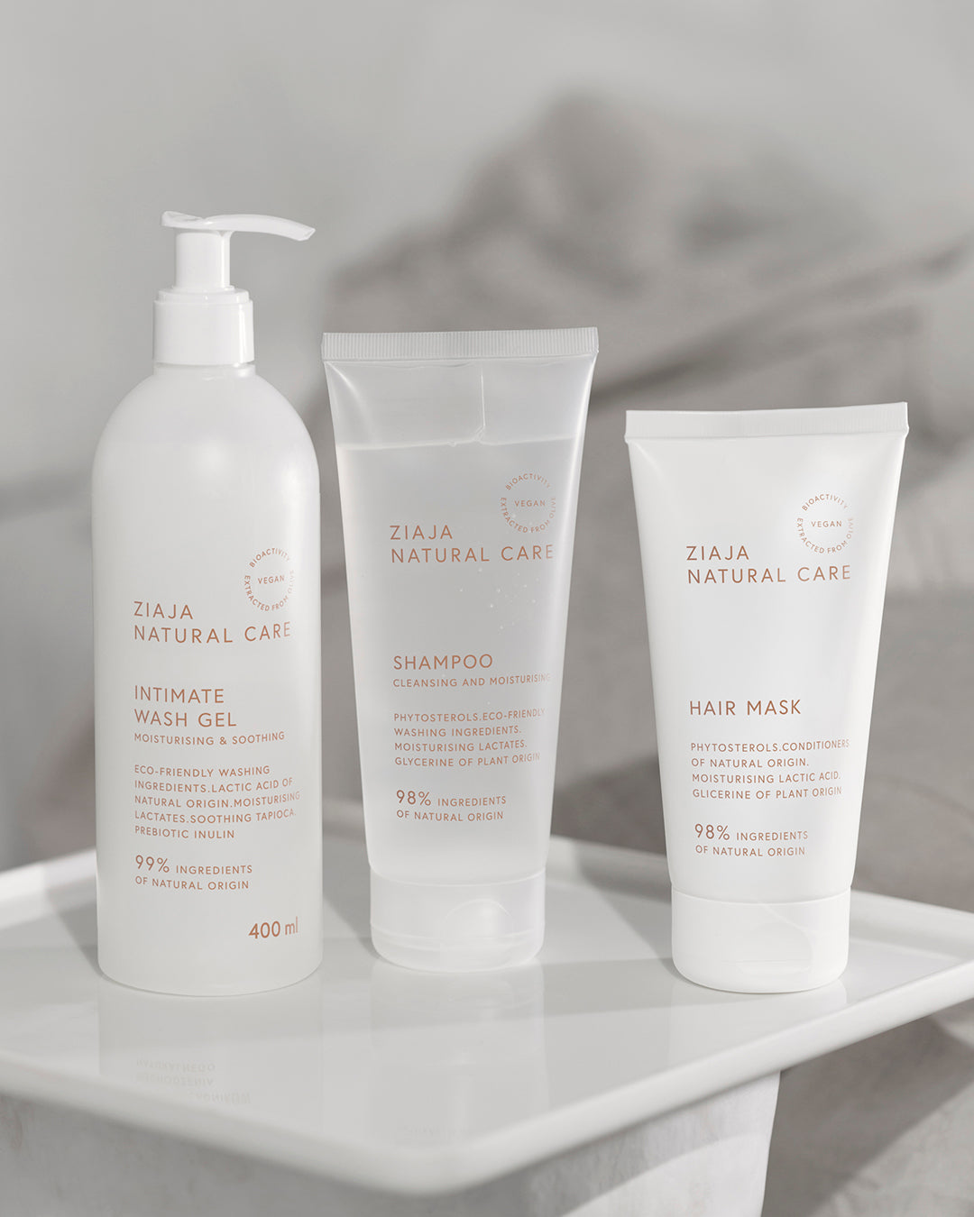 Ziaja Natural Care products including Intimate Wash Gel, Shampoo, and Hair Mask on a white surface with a gray background.