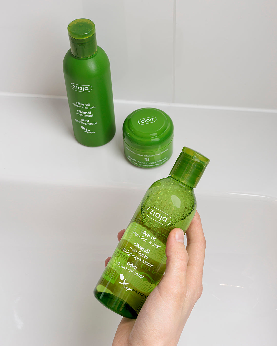Person holding a green Ziaja olive oil bottle of micellar water