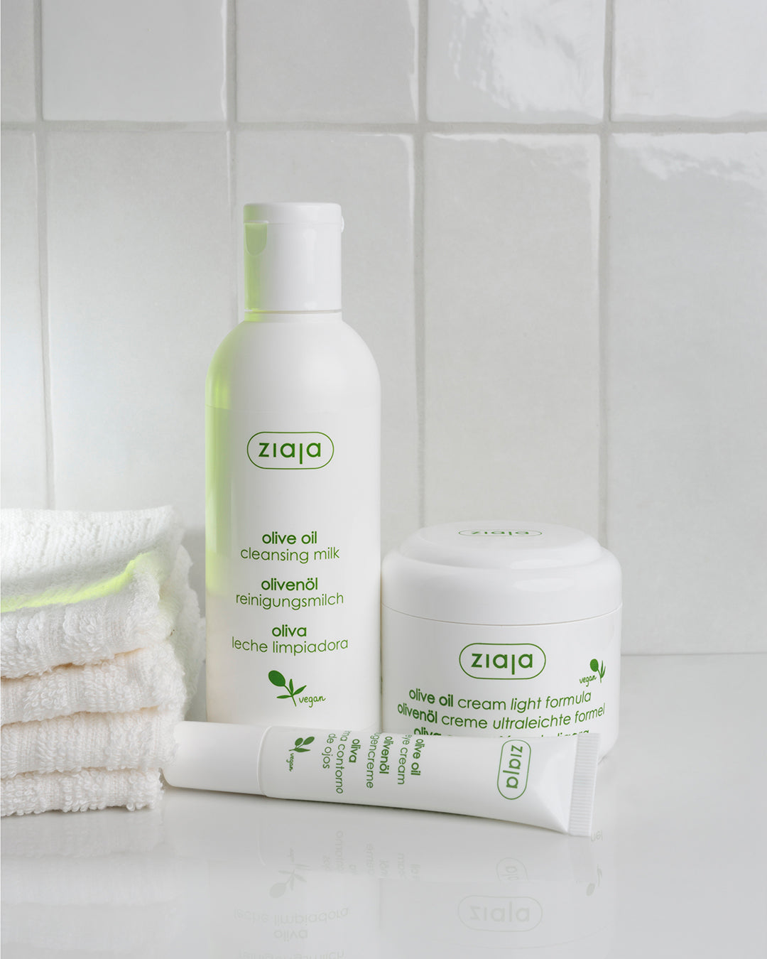 Ziaja skincare products including a bottle and tube on a tiled bathroom counter.