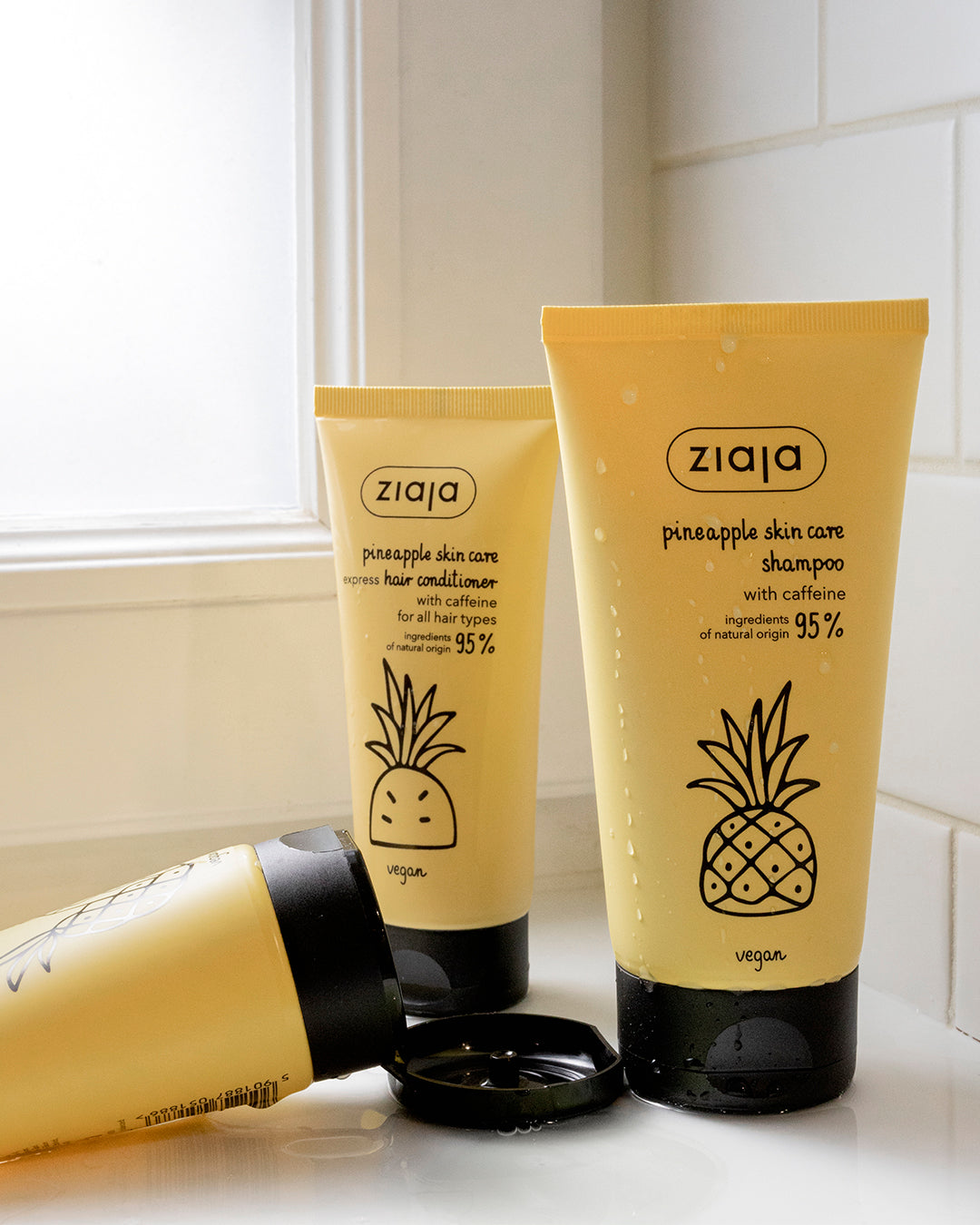 Ziaja pineapple hair care shampoo and conditioner with caffeine, vegan yellow tubes in bathroom setting, natural origin haircare products