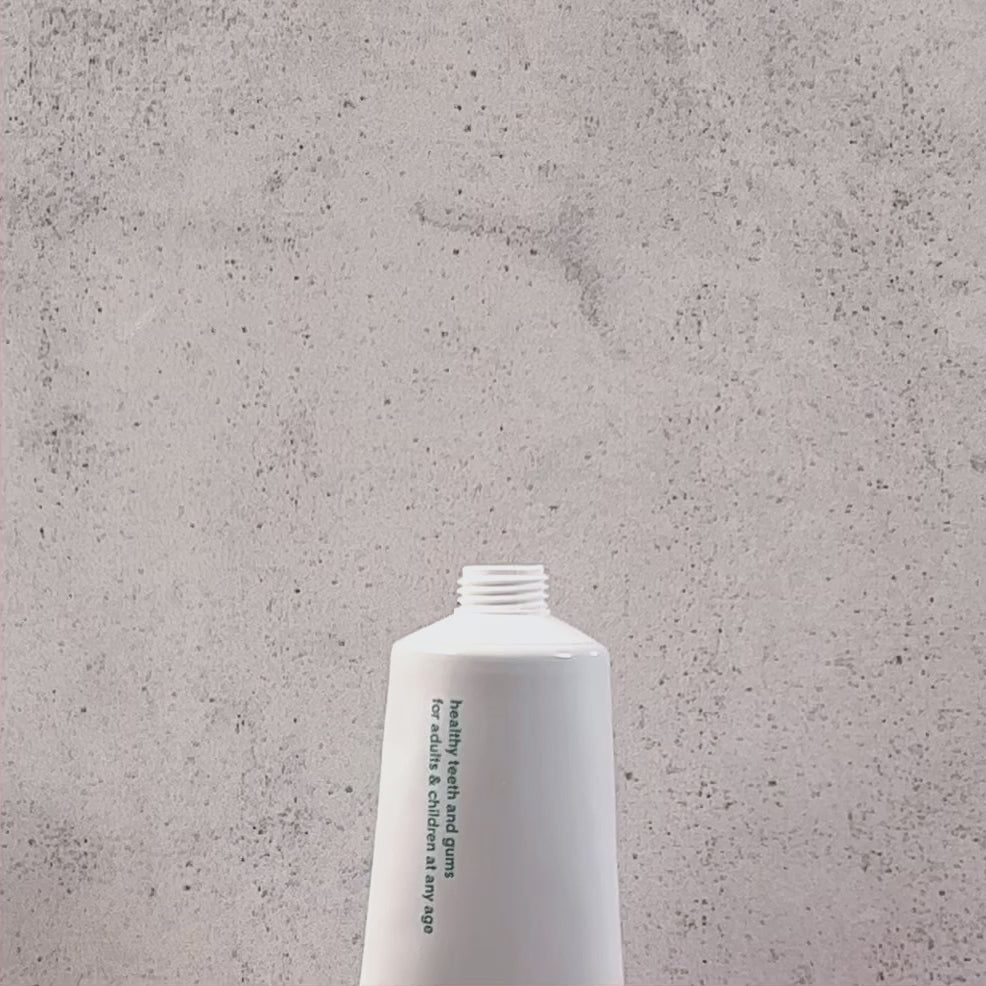 Close-up video of Ziaja Mintperfect Sage Fluoride-Free Toothpaste with green gel toothpaste squeezed onto the tube opening against a grey background.