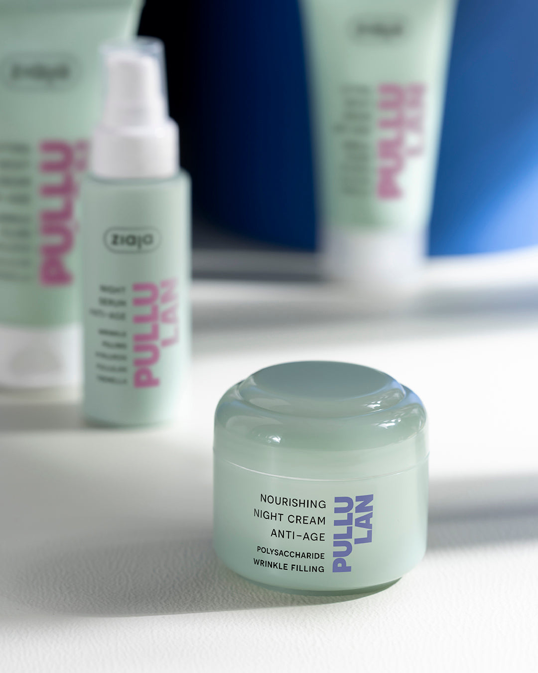 Jar of Pullulan nourishing night cream on a white surface with blurred skincare products in the background.