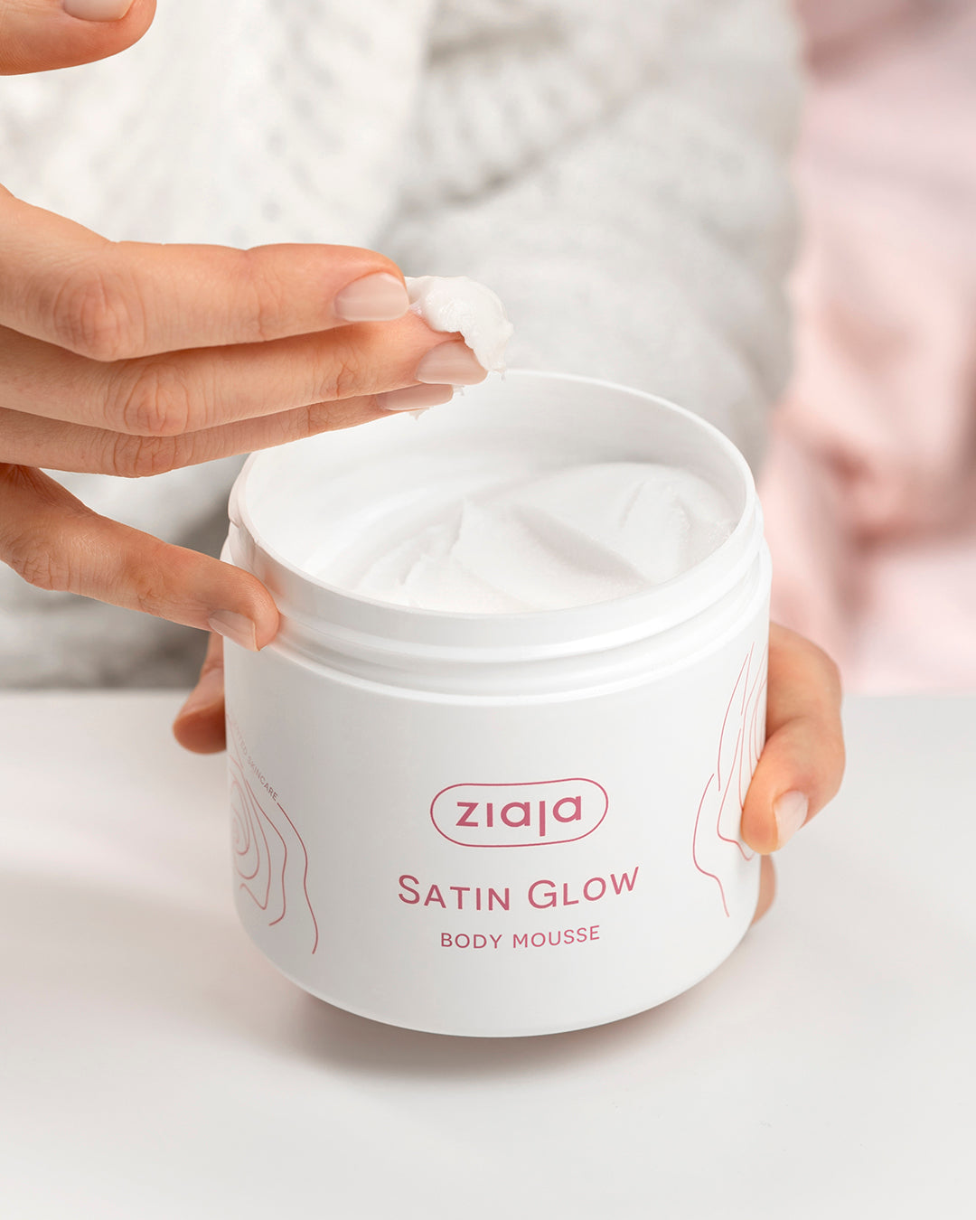 Person holding a jar of Ziaja Satin Glow Body Mousse on a light background