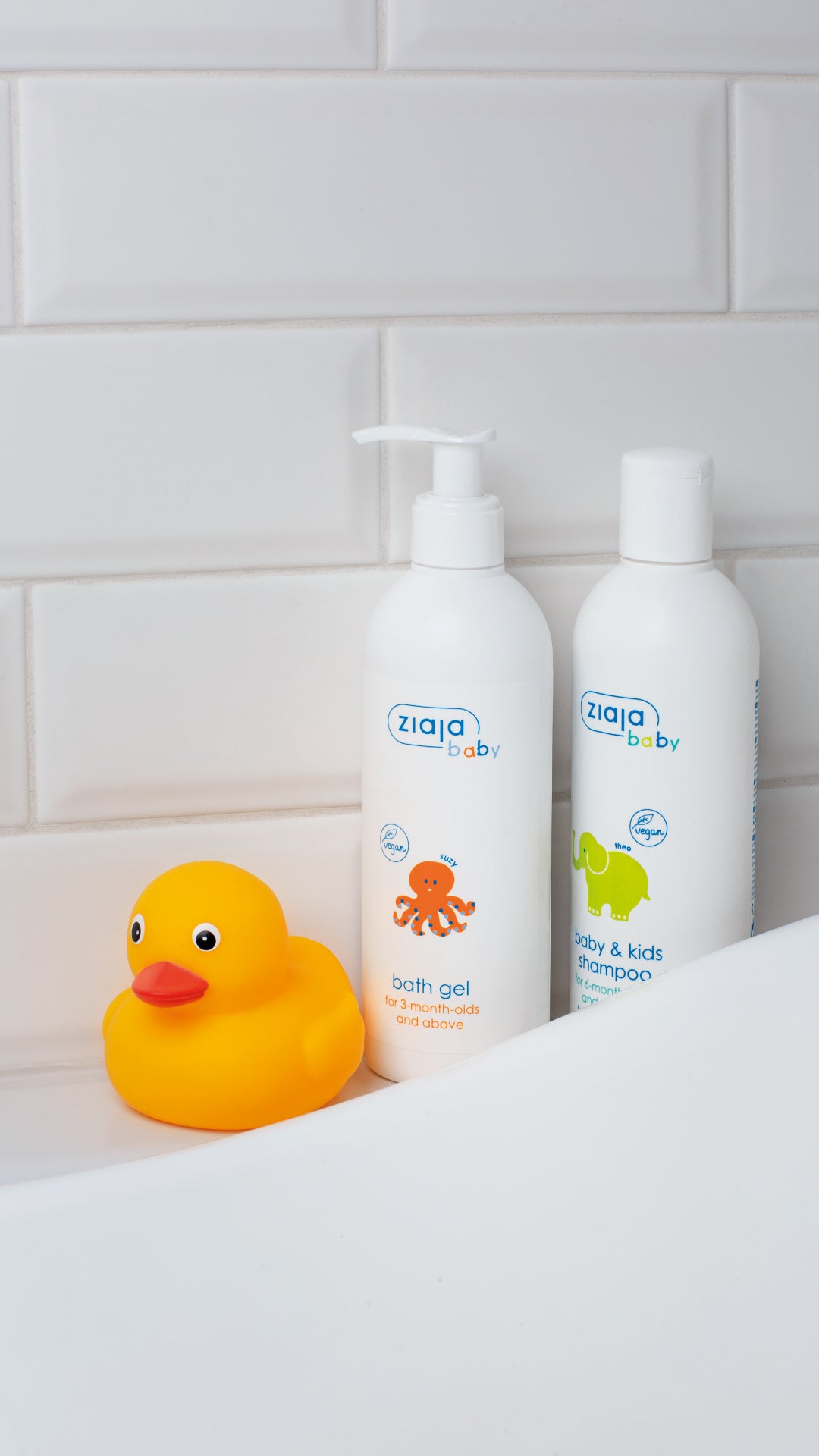 Ziaja Baby Bath Gel and Ziaja Baby & Kids Shampoo bottles next to a yellow rubber duck on the edge of a bathtub.