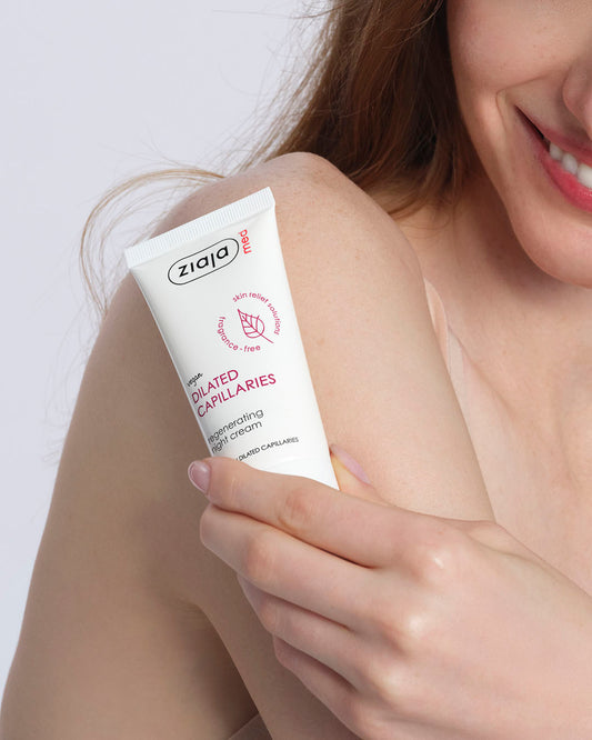 Woman holding a tube of Ziaja cream on a white background