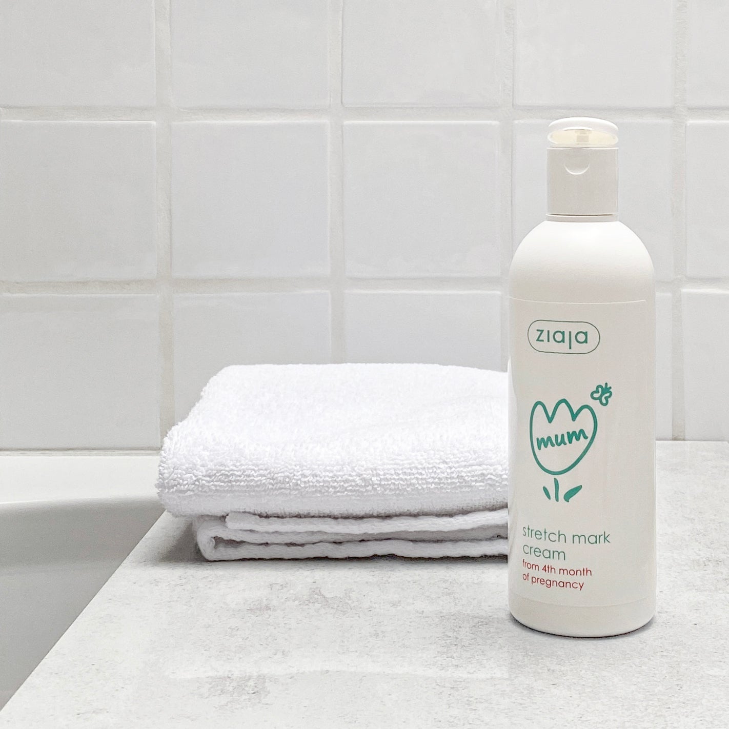 Ziaja Mum stretch mark cream bottle on a bathroom counter with a towel in the background.