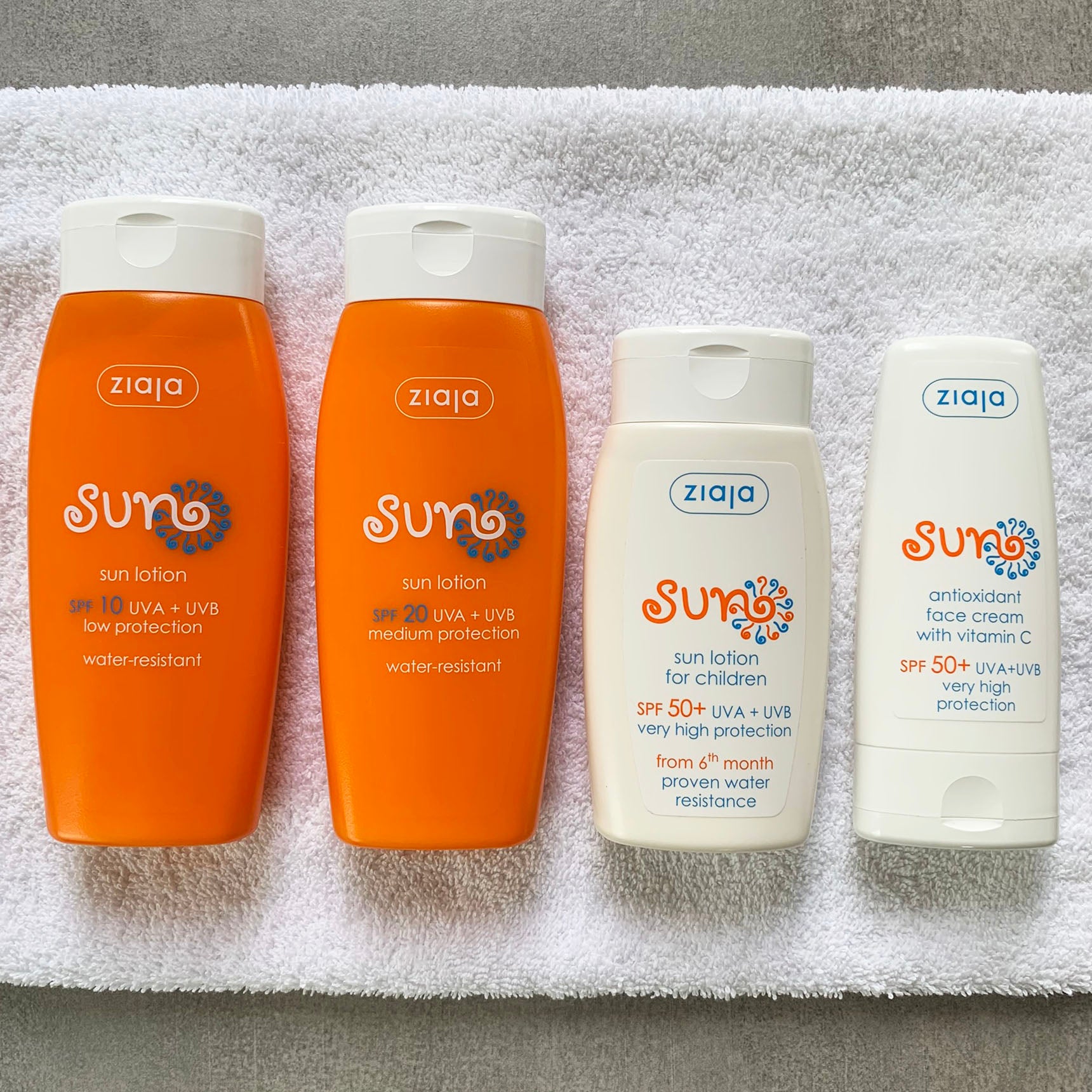 Ziaja Sun range on a white towel – SPF 10 and SPF 20 sun lotions, SPF 50+ children’s sun lotion and SPF 50+ face cream