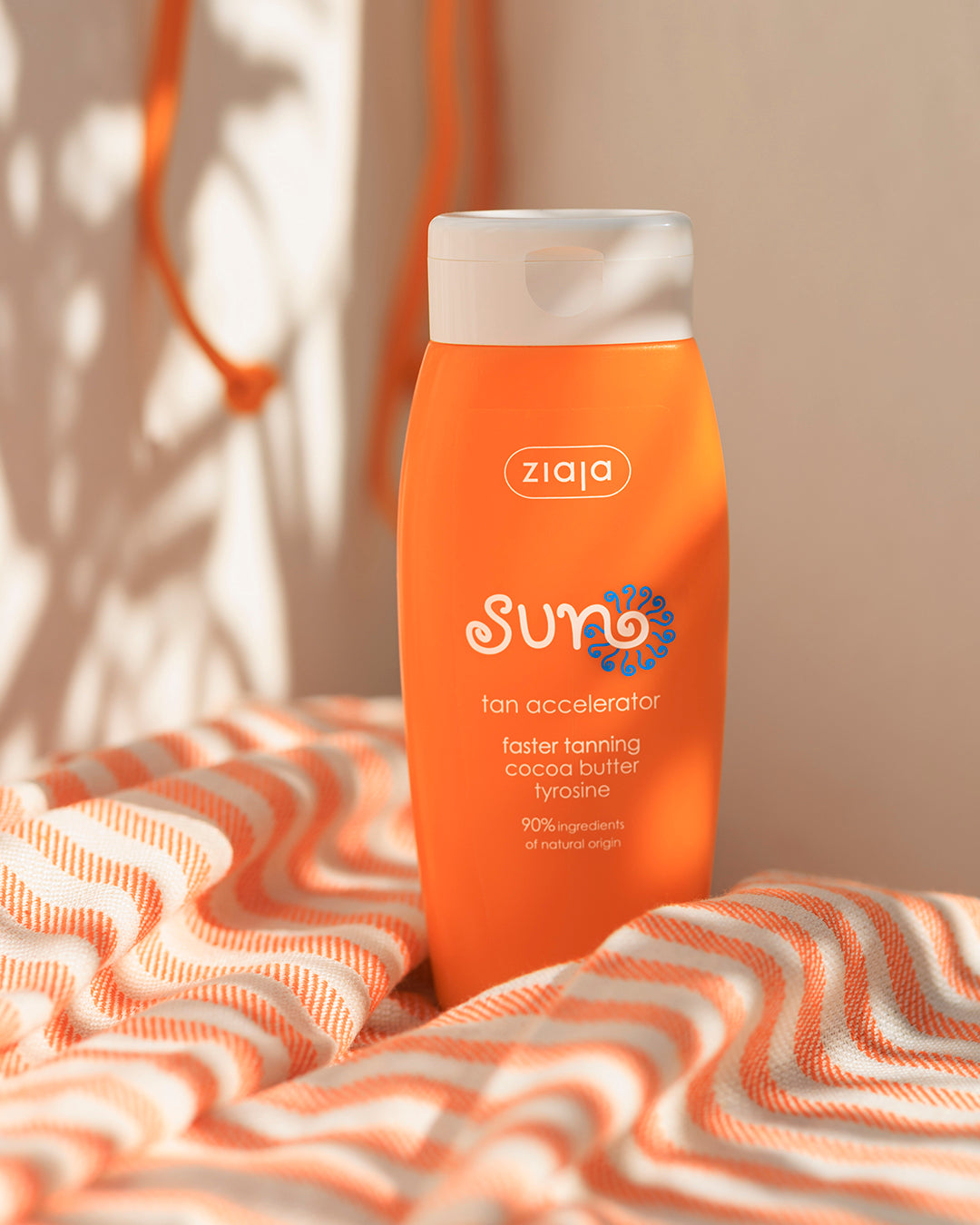 Ziaja Sun Tan Accelerator bottle on a striped beach towel in warm sunlight